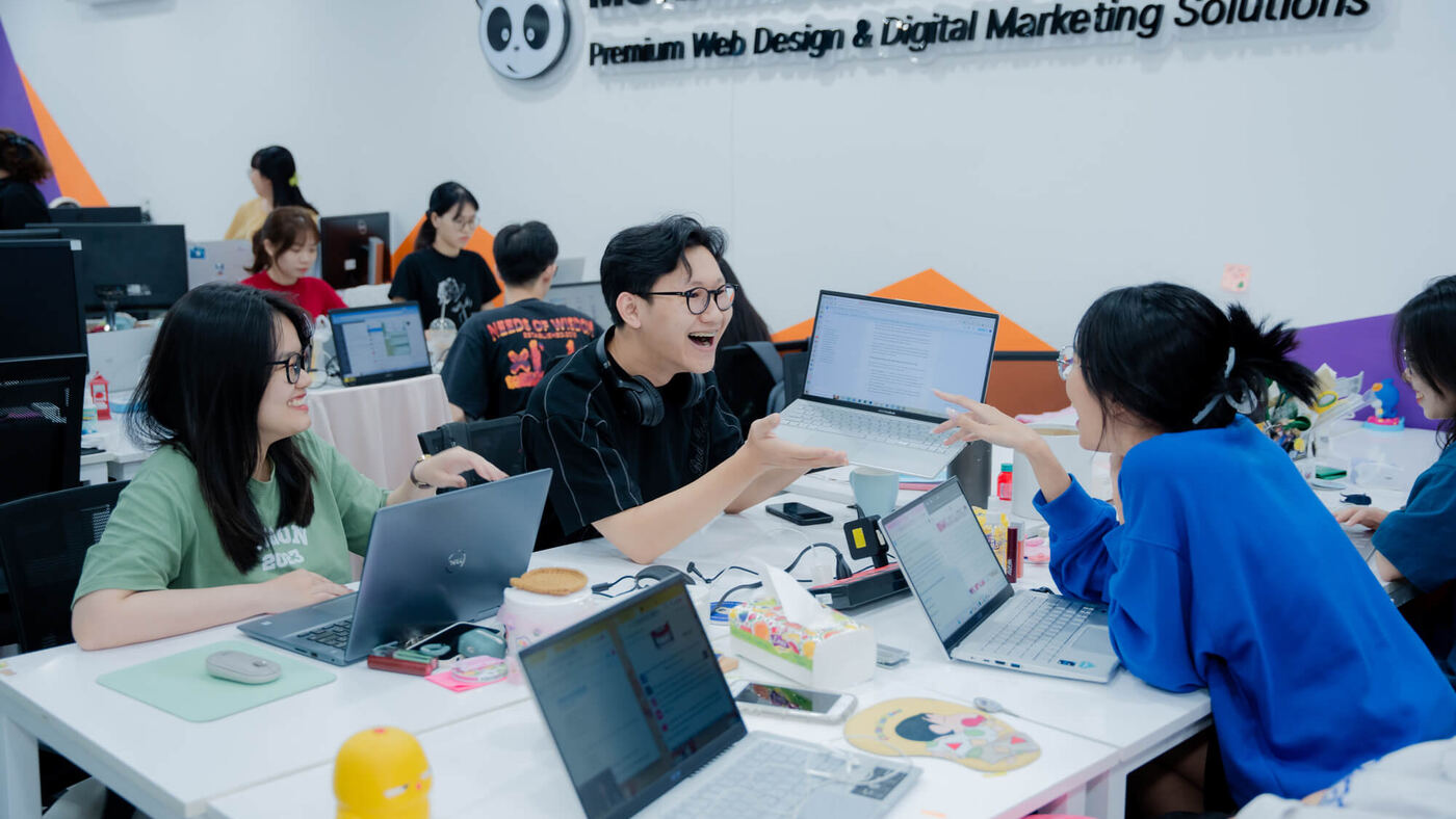 Phòng Marketing MONA Media thảo luận dự án bên laptop đầu tuần